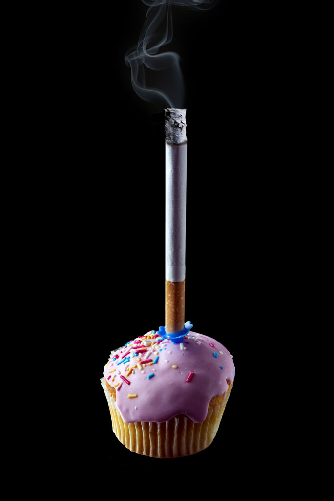 Funny photo of a cigarette on top of a cup cake.